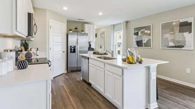 a kitchen that has a lot of white cabinets and stainless steel appliances