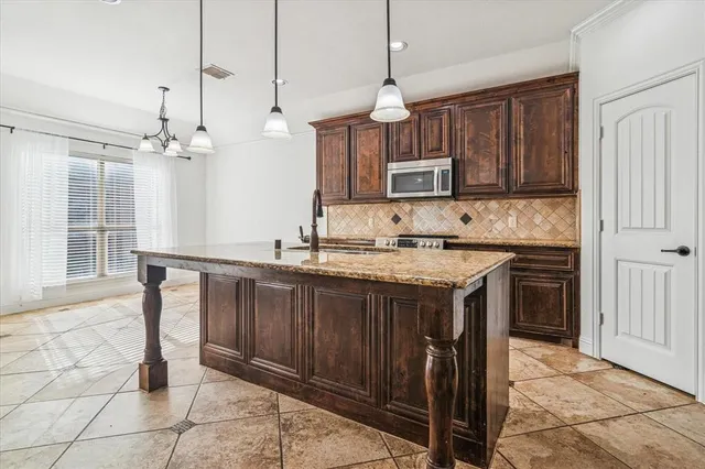 a kitchen with kitchen island granite countertop a stove a sink and a cabinets