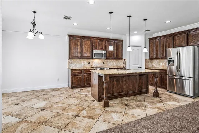 a kitchen with stainless steel appliances granite countertop a stove a sink a refrigerator and a wooden cabinets