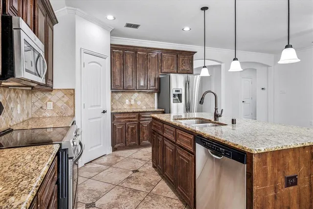 a kitchen with stainless steel appliances granite countertop a sink a stove and a refrigerator