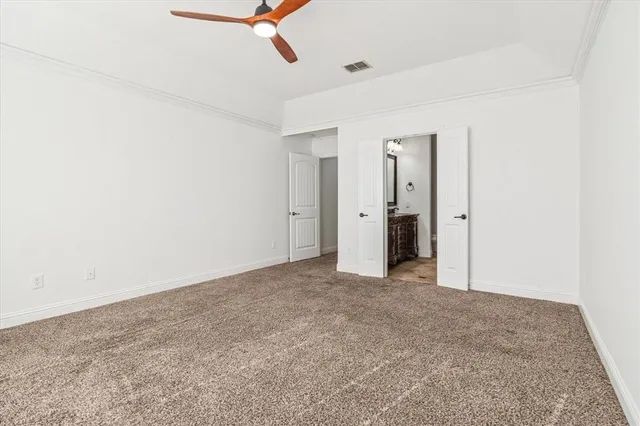 an empty room with closet and a ceiling fan