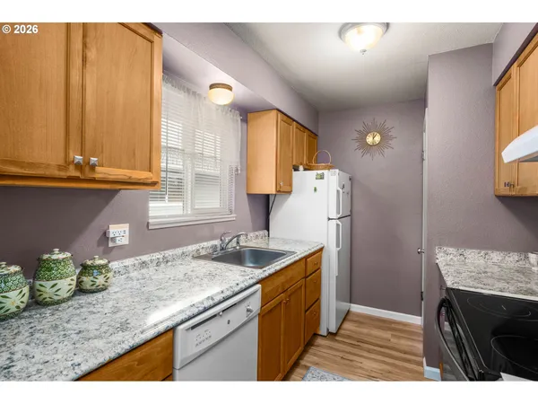 a kitchen with granite countertop a sink a stove and refrigerator