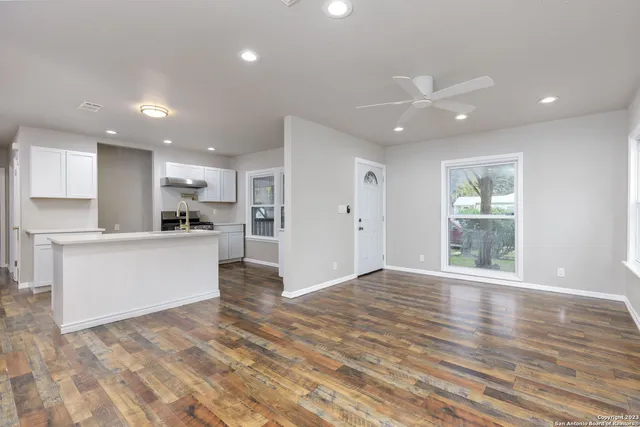 a view of large kitchen with kitchen island a sink wooden floor and a refrigerator