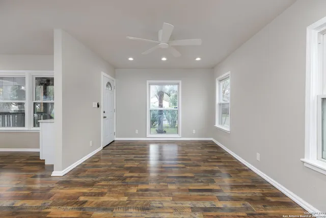 a view of an empty room with wooden floor and a window