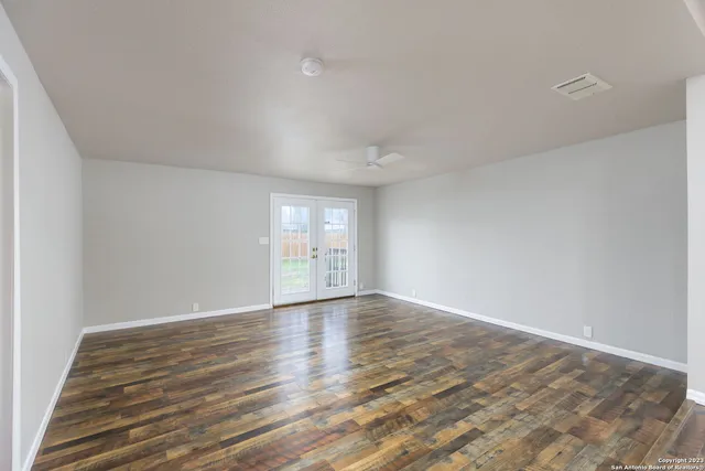 a view of an empty room with wooden floor and a window