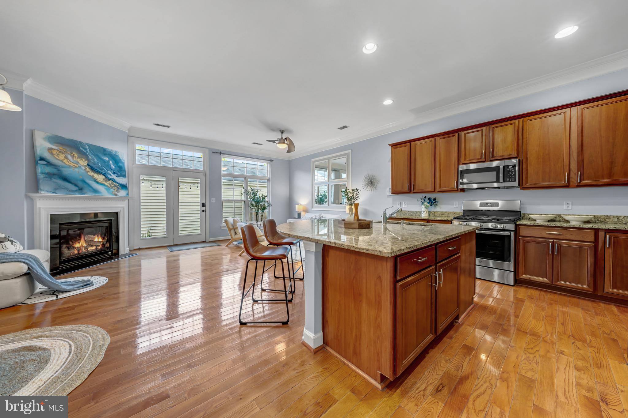 9231 Ribbon Falls Loop Bristow, VA 20136 - Photo 15 of 40 a kitchen with stainless steel appliances granite countertop a stove top oven a sink dishwasher a dining table and chairs with wooden floor