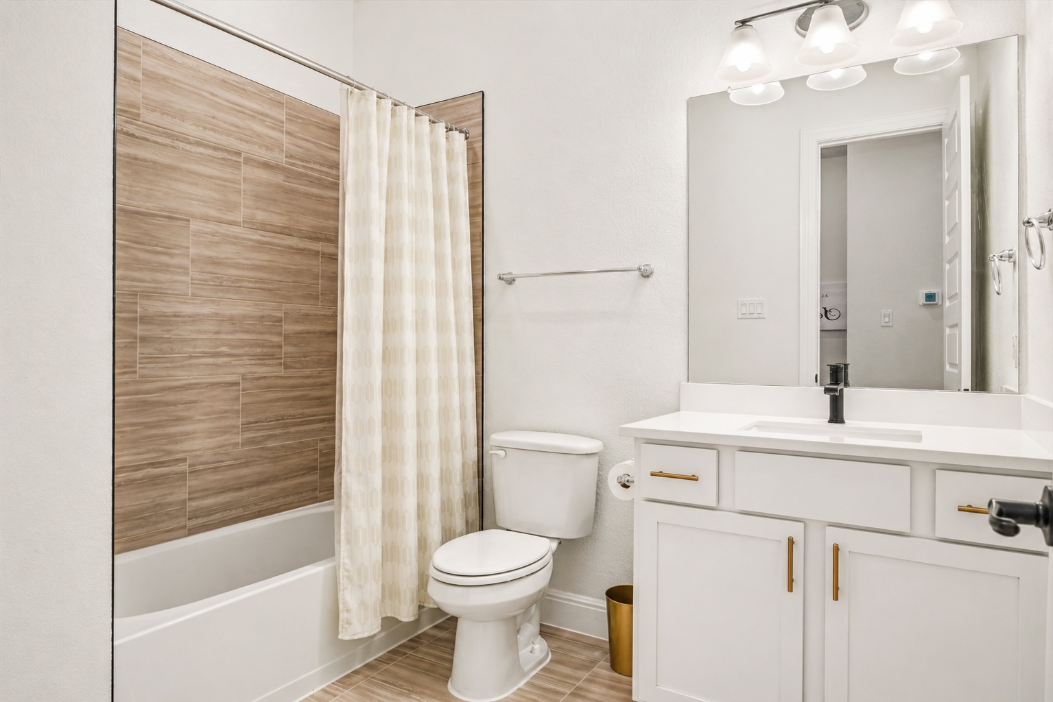 209 Rainier Drive Kyle, TX 78640 - Photo 18 of 24 Full bathroom featuring a white vanity with gold-tone hardware, a white countertop, and an integrated rectangular sink with a matte black faucet