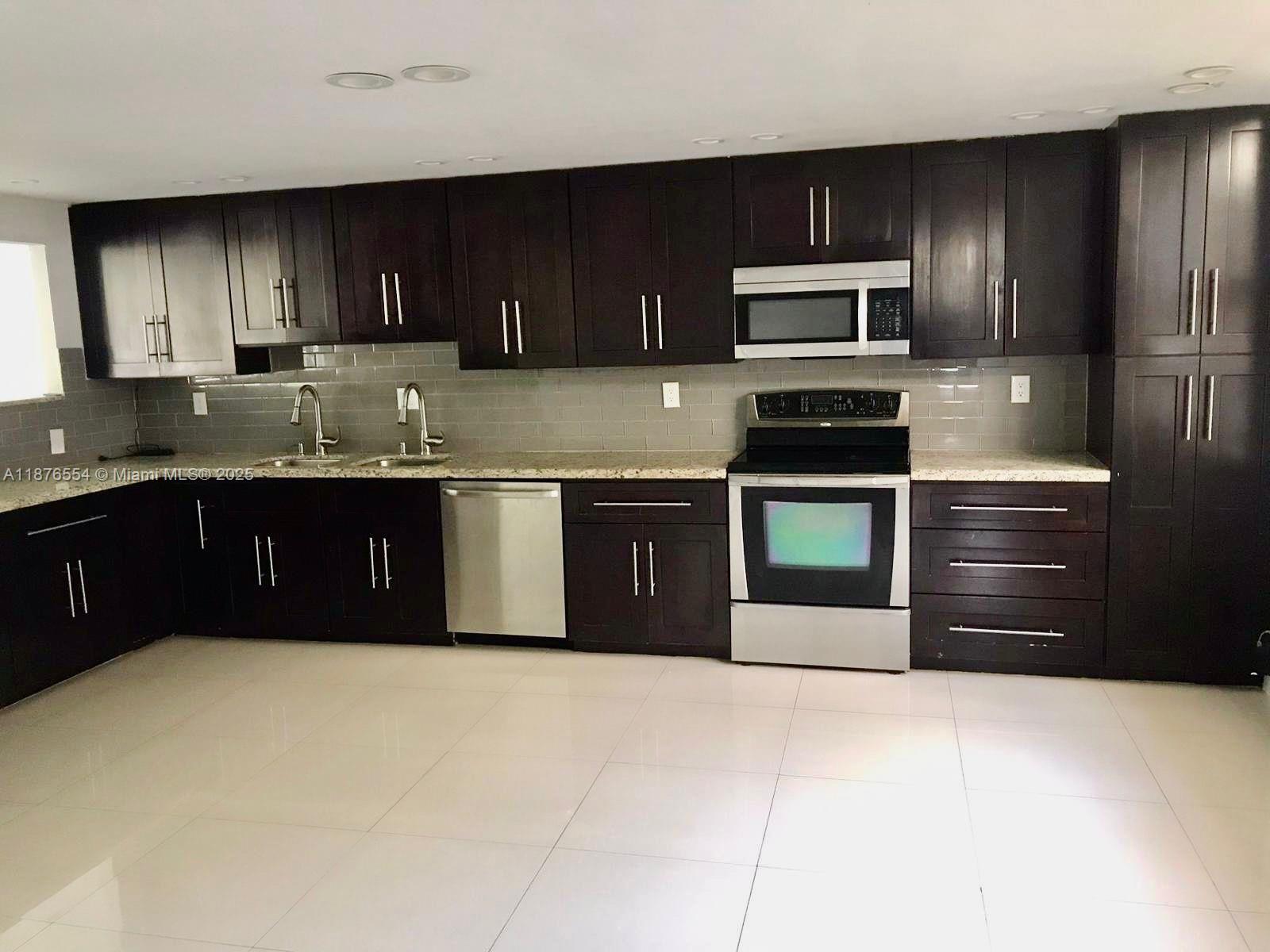 20381 Northeast 30th Avenue, Unit 2067 Aventura, FL 33180 - Photo 2 of 17 a kitchen with stainless steel appliances granite countertop a stove microwave and refrigerator