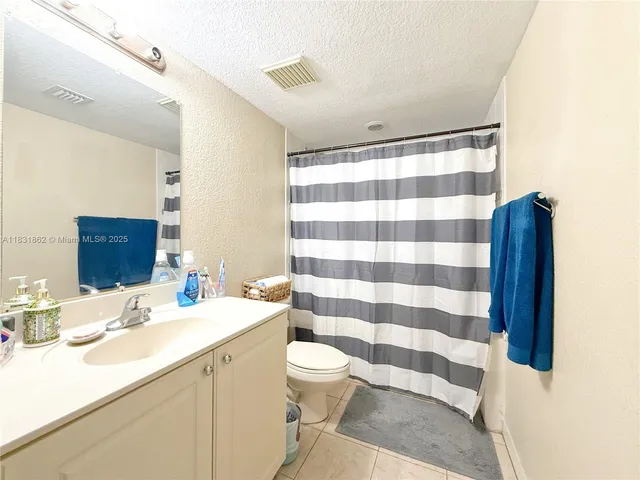 a bathroom with a sink a toilet a mirror and shower curtain