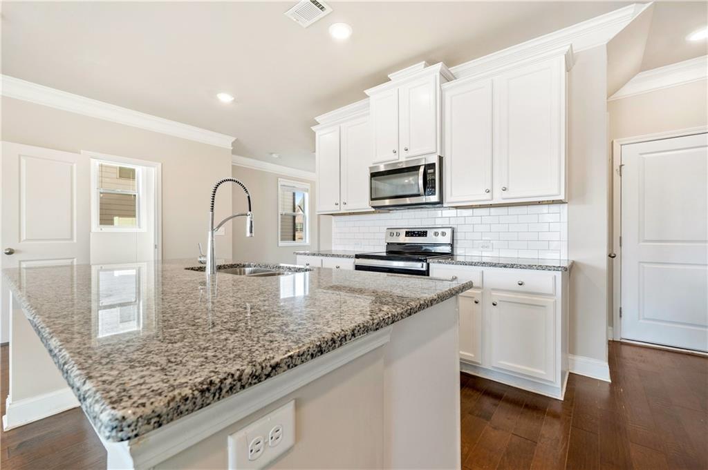 2747 Pearl Rdg Trace Buford, GA 30519 - Photo 6 of 41 a kitchen with kitchen island granite countertop a stove top oven a sink a counter space and cabinets