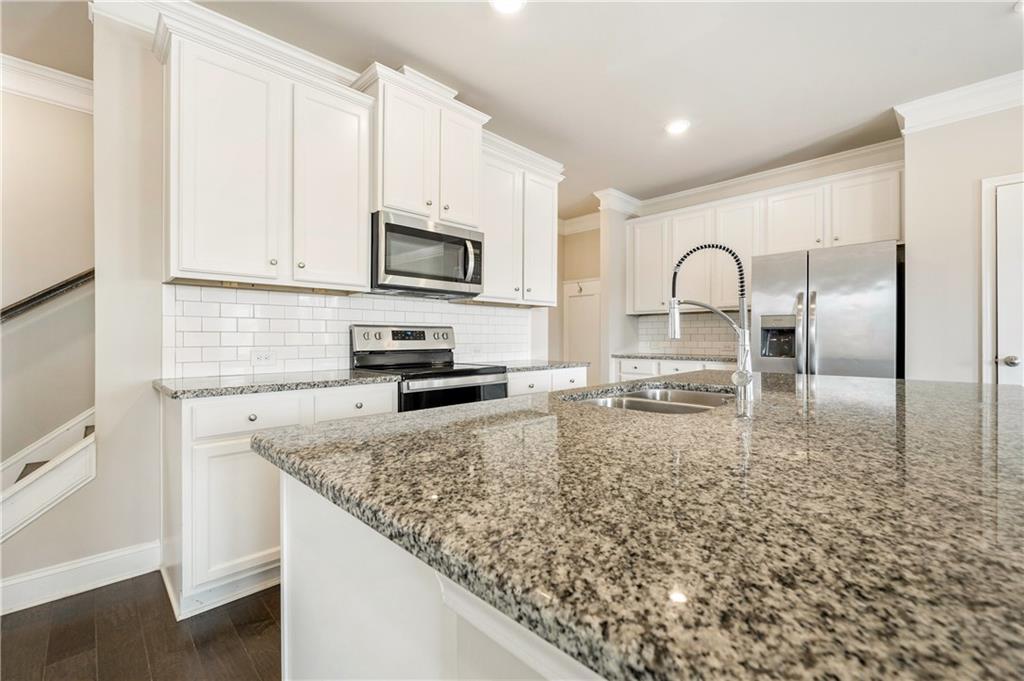 2747 Pearl Rdg Trace Buford, GA 30519 - Photo 7 of 41 a kitchen with granite countertop a stove a sink and a microwave