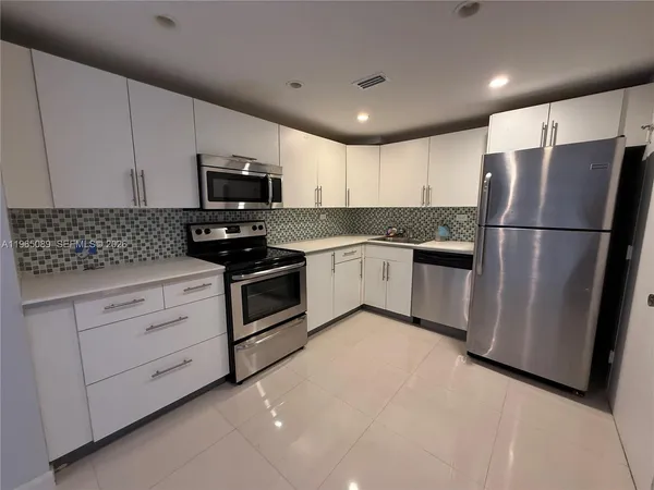 a kitchen with white cabinets stainless steel appliances and a refrigerator