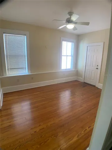 a view of wooden floor and a chandelier fan in a room