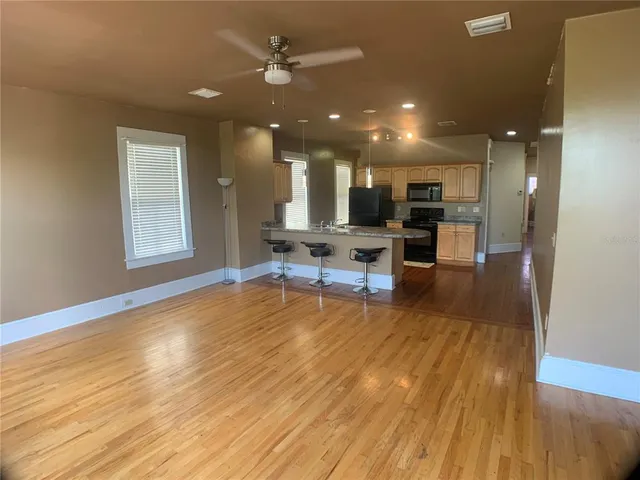 a living room with furniture and kitchen view with wooden floor
