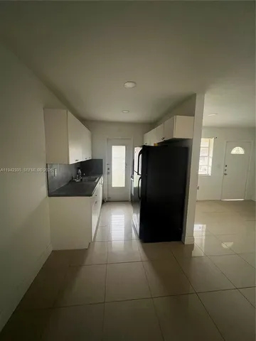 a view of a refrigerator in kitchen and empty room