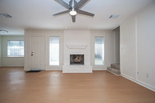 an empty room with windows and fireplace