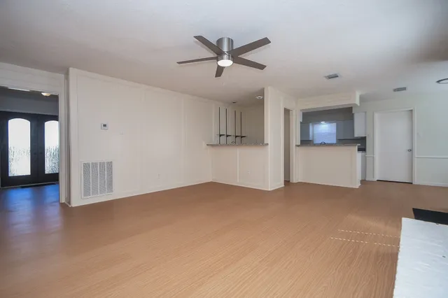 a view of empty room with wooden floor and ceiling fan