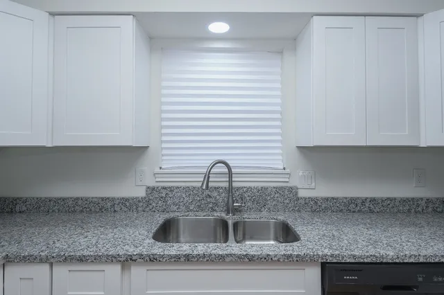 a kitchen with granite countertop a sink and cabinets