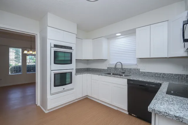a kitchen with granite countertop white cabinets and white appliances