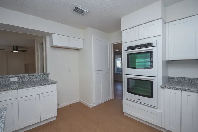 a kitchen with white cabinets and oven