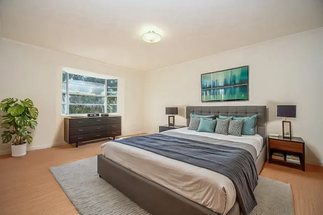 a spacious bedroom with a bed a couch and potted plant on the dresser