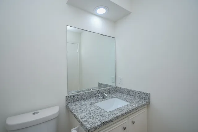 a bathroom with a granite countertop sink and toilet