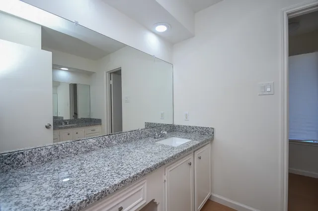 a bathroom with a granite countertop sink and a mirror