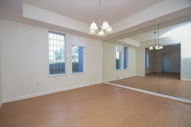 an empty room with chandelier fan and windows