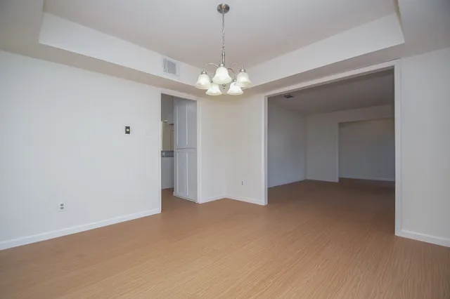 a view of an empty room with chandelier fan