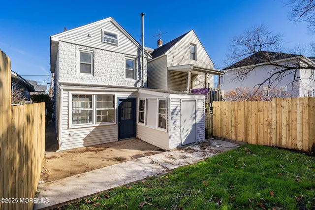 a view of a house with backyard and wooden fence