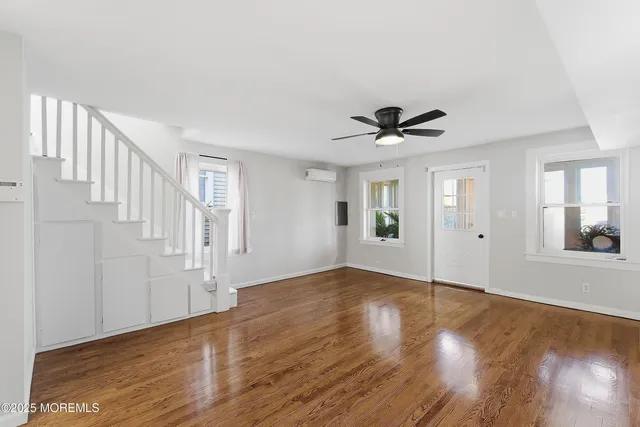 a view of a livingroom with wooden floor and a ceiling fan