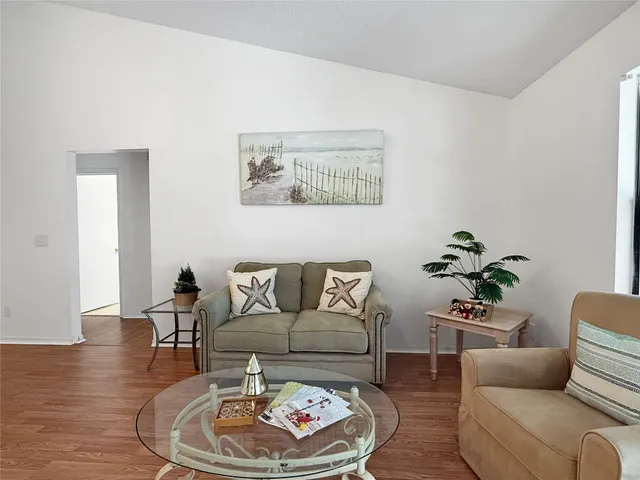 a living room with furniture and a dining table with wooden floor