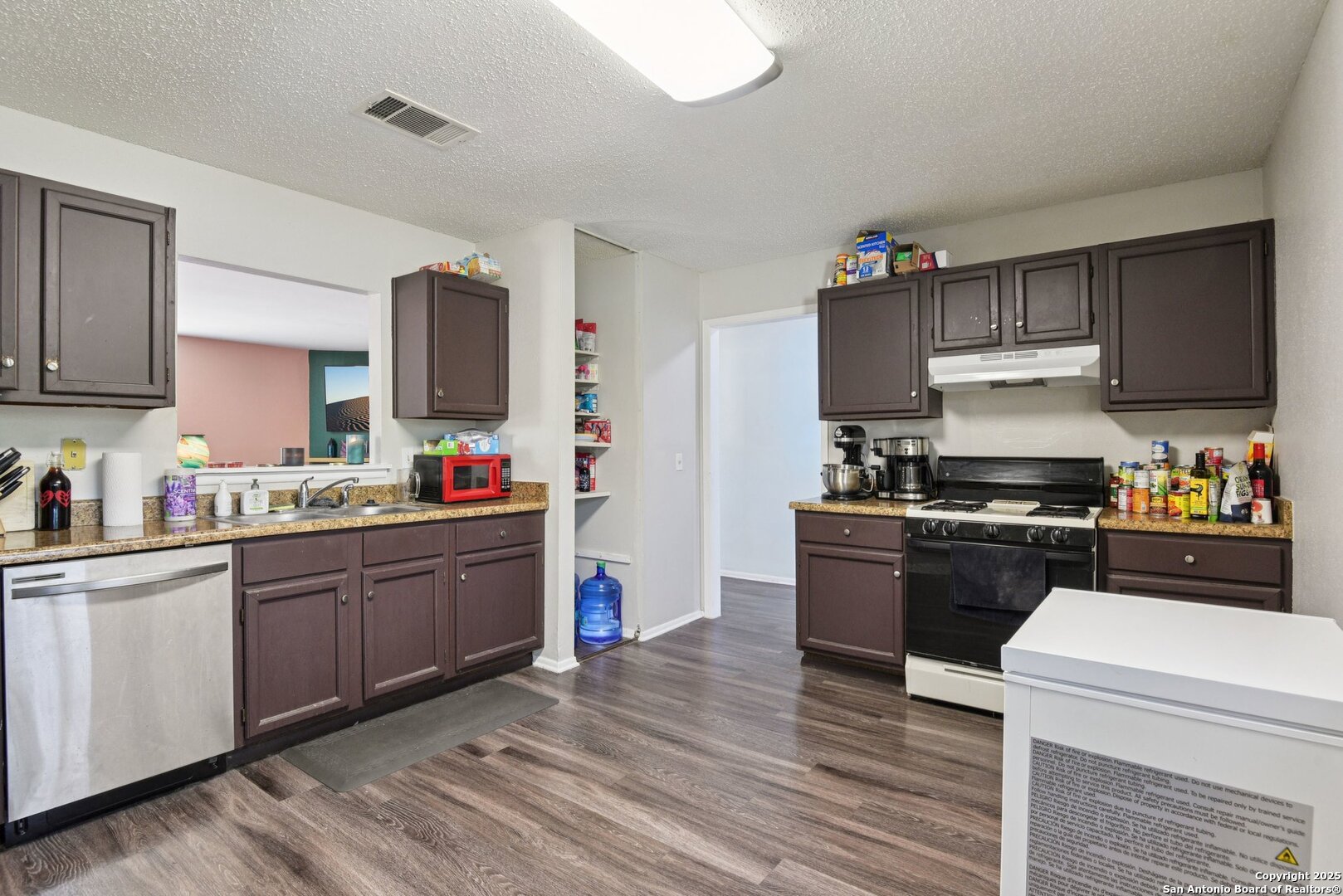 113 Friendswood Path Universal City, TX 78148 - Photo 19 of 40 a kitchen with stainless steel appliances granite countertop a stove top oven a sink dishwasher and a refrigerator with wooden floor