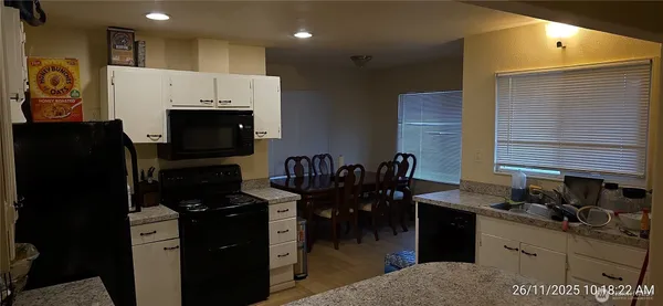 a kitchen with granite countertop white cabinets and black appliances