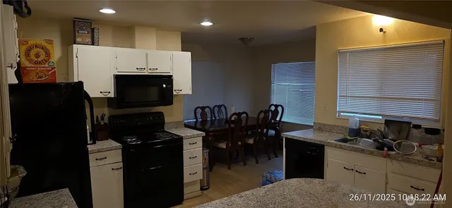 a kitchen with granite countertop white cabinets and black appliances