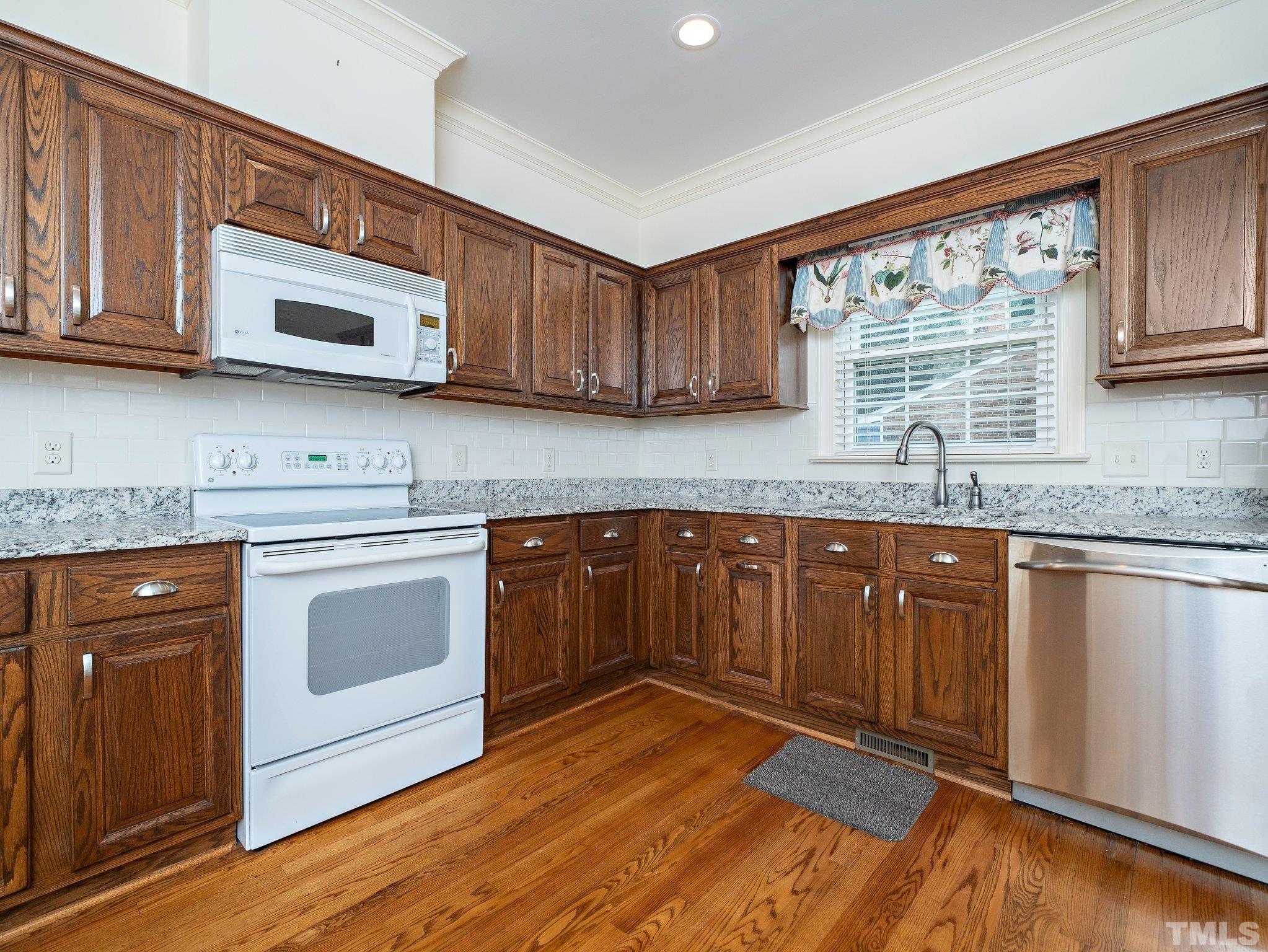 417 Weathergreen Drive Raleigh, NC 27615 - Photo 11 of 37 a kitchen with granite countertop wooden cabinets stainless steel appliances and a window