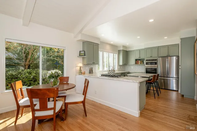 a kitchen with stainless steel appliances granite countertop a stove a refrigerator a kitchen island a table and chairs in it