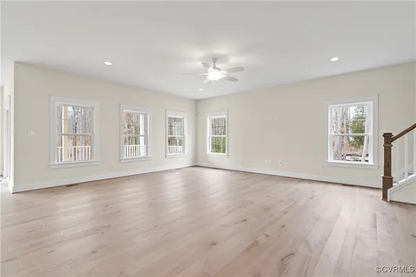 a view of an empty room with a window and wooden floor