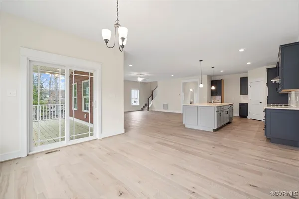 a view of a kitchen with kitchen island stainless steel appliances wooden floor and a chandelier