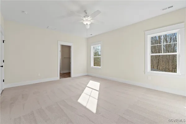 an empty room with windows and chandelier fan