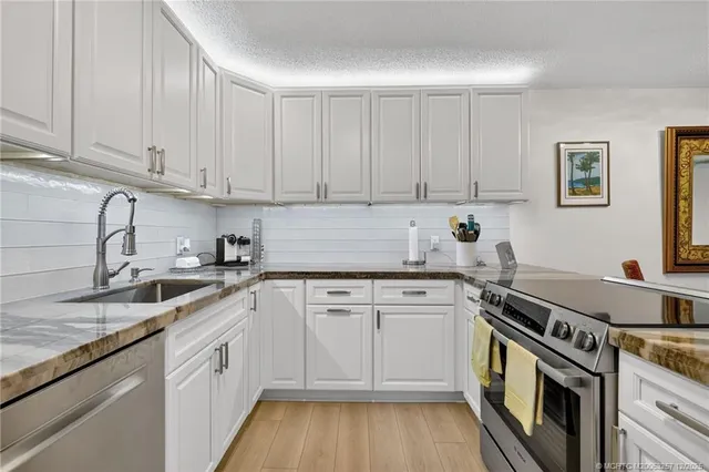a kitchen with granite countertop white cabinets and white appliances