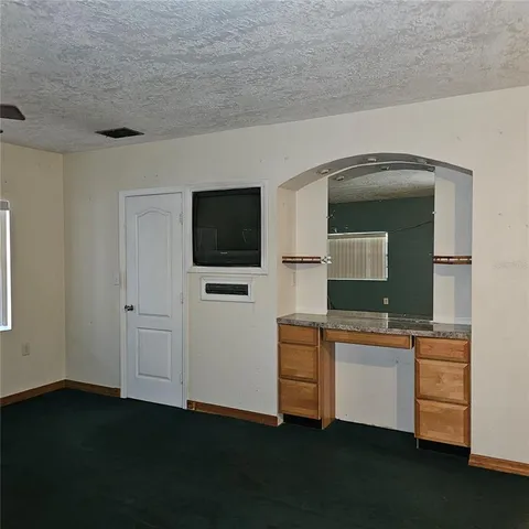 a room with a flat screen tv and kitchen view
