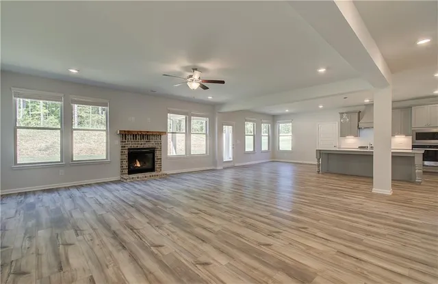 an empty room with wooden floor fireplace and windows