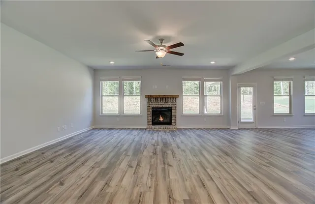 an empty room with wooden floor fireplace and windows