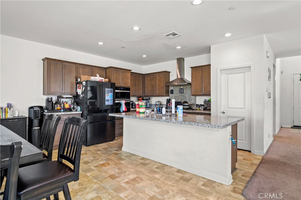 774 Green Court Perris, CA 92571 - Photo 5 of 25 a kitchen with stainless steel appliances granite countertop a refrigerator a stove a sink a dining table and chairs