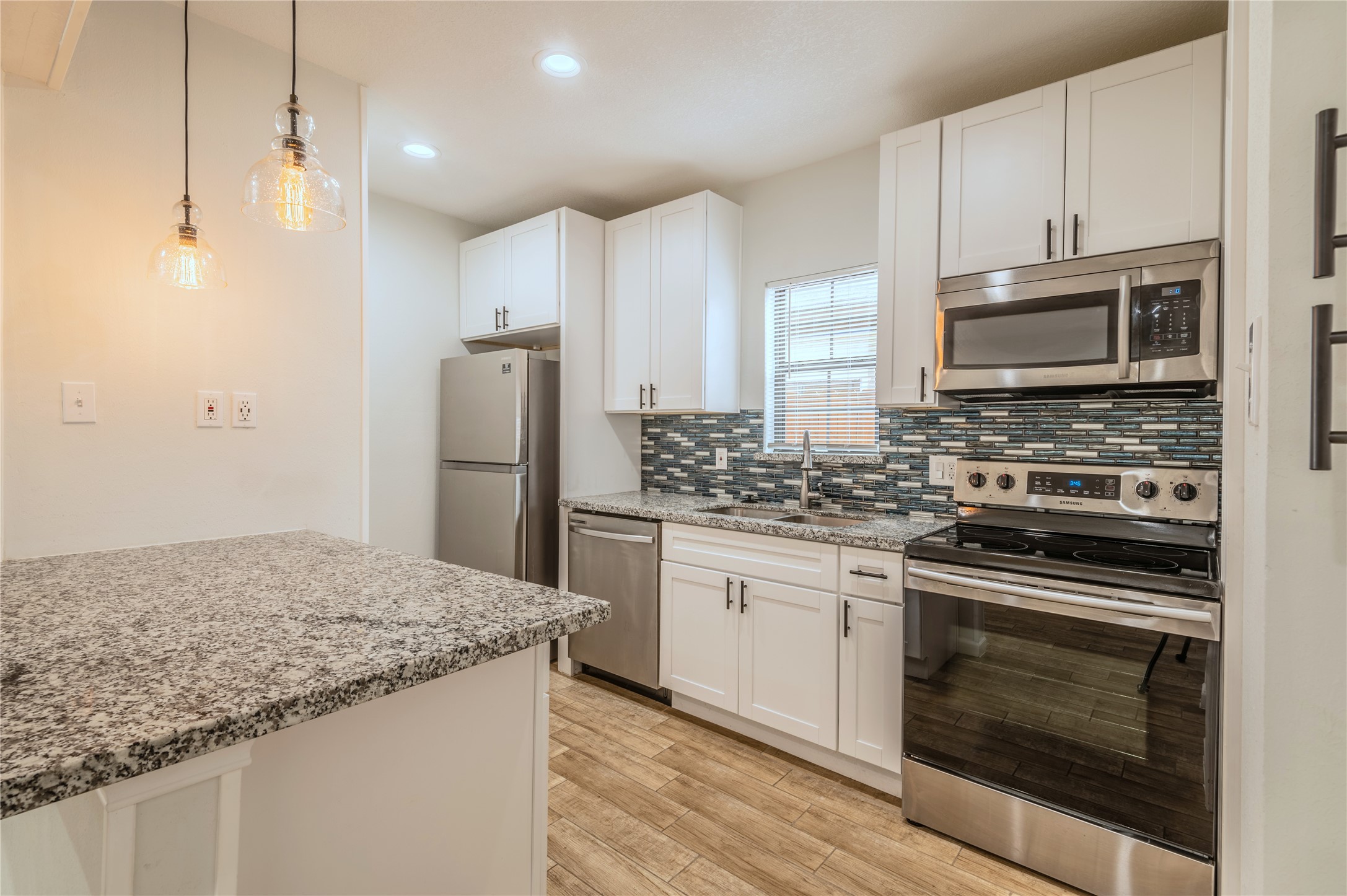 2319 Rosewood Street, Unit A Houston, TX 77004 - Photo 7 of 15 a kitchen with granite countertop wooden cabinets sink and stainless steel appliances