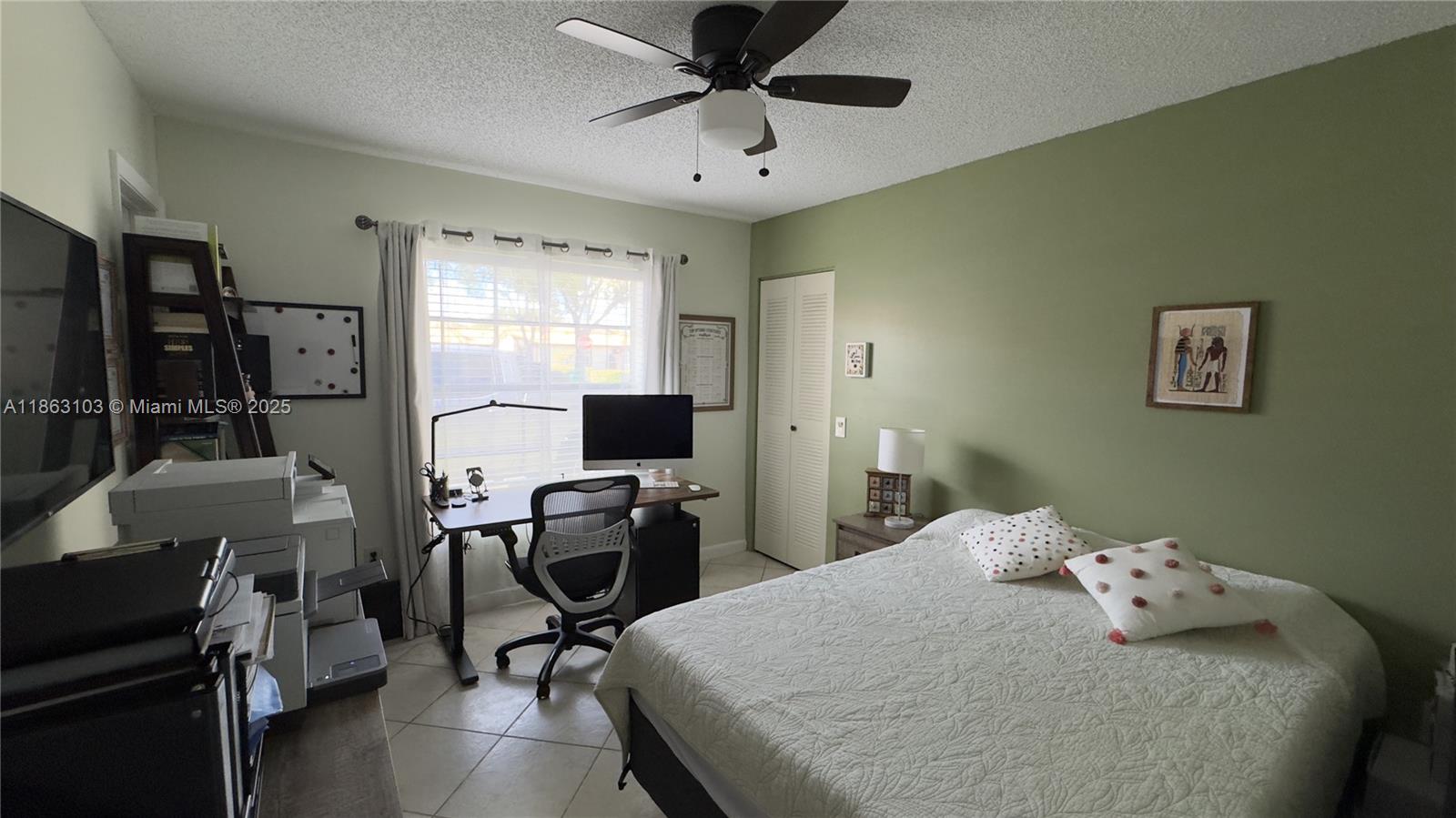 15205 Southwest 45th Terrace, Unit 45E Miami, FL 33185 - Photo 6 of 9 a bedroom with a bed and a flat screen tv