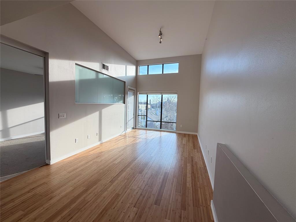 4040 North Hall Street, Unit 309 Dallas, TX 75219 - Photo 14 of 18 a view of an empty room with wooden floor and a window