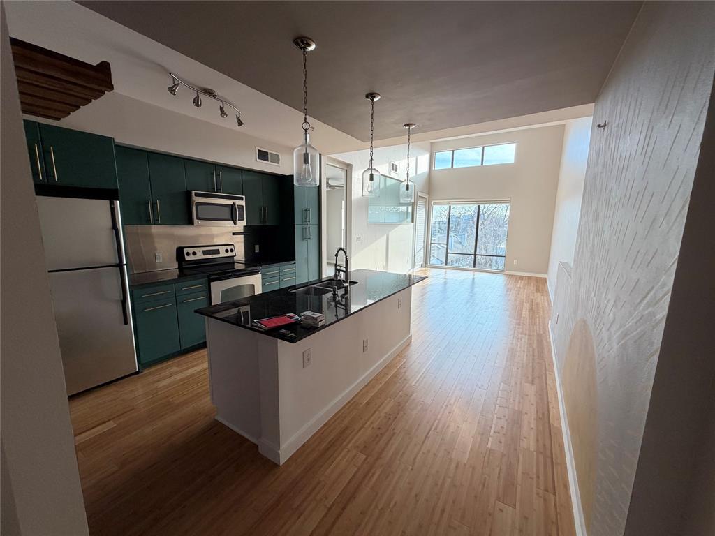 4040 North Hall Street, Unit 309 Dallas, TX 75219 - Photo 3 of 18 a kitchen with stainless steel appliances a refrigerator a sink a stove a microwave and wooden floors