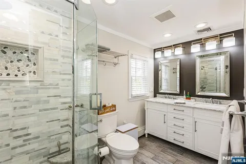 a bathroom with a double vanity sink toilet mirror and shower